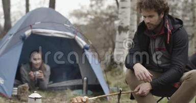 在露营帐篷附近做饭的男人和女朋友。热狗宽镜头。情侣恋<strong>秋游</strong>